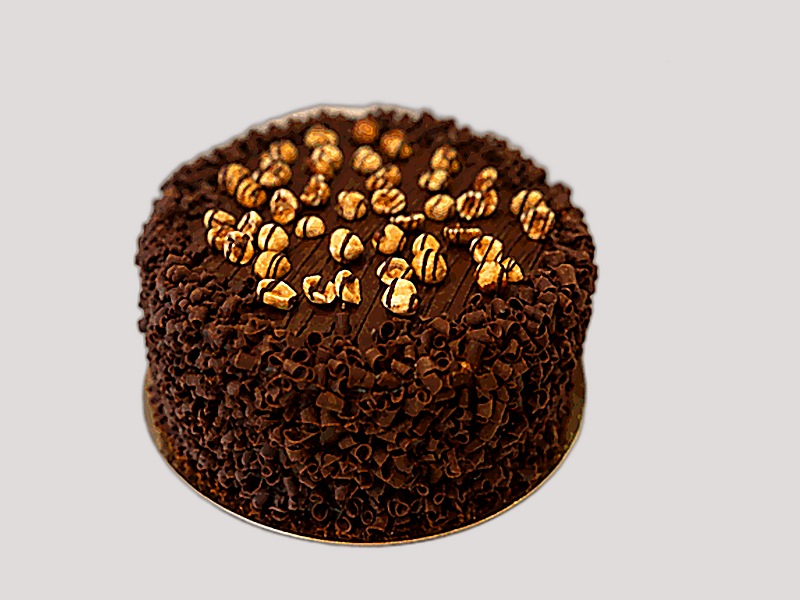 Whole hazelnut chocolate cake covered in chocolate curls and topped with toasted hazelnuts