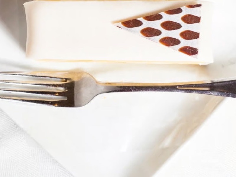 Almond Debutante slice with a chocolate-dotted almond tuile, served with a fork