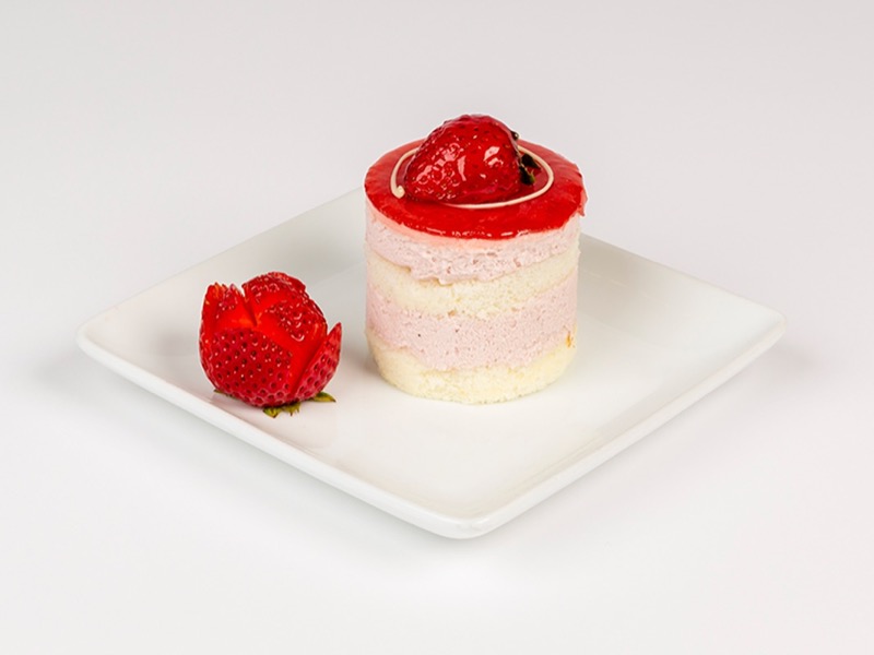 Individual strawberry mousse cake with a red glaze and a sugar rose