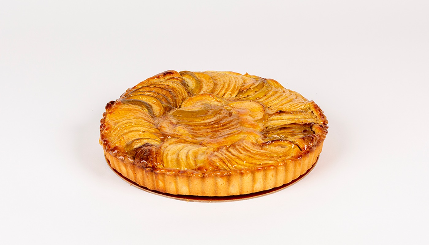 A round tart topped with fanned, glazed apple slices